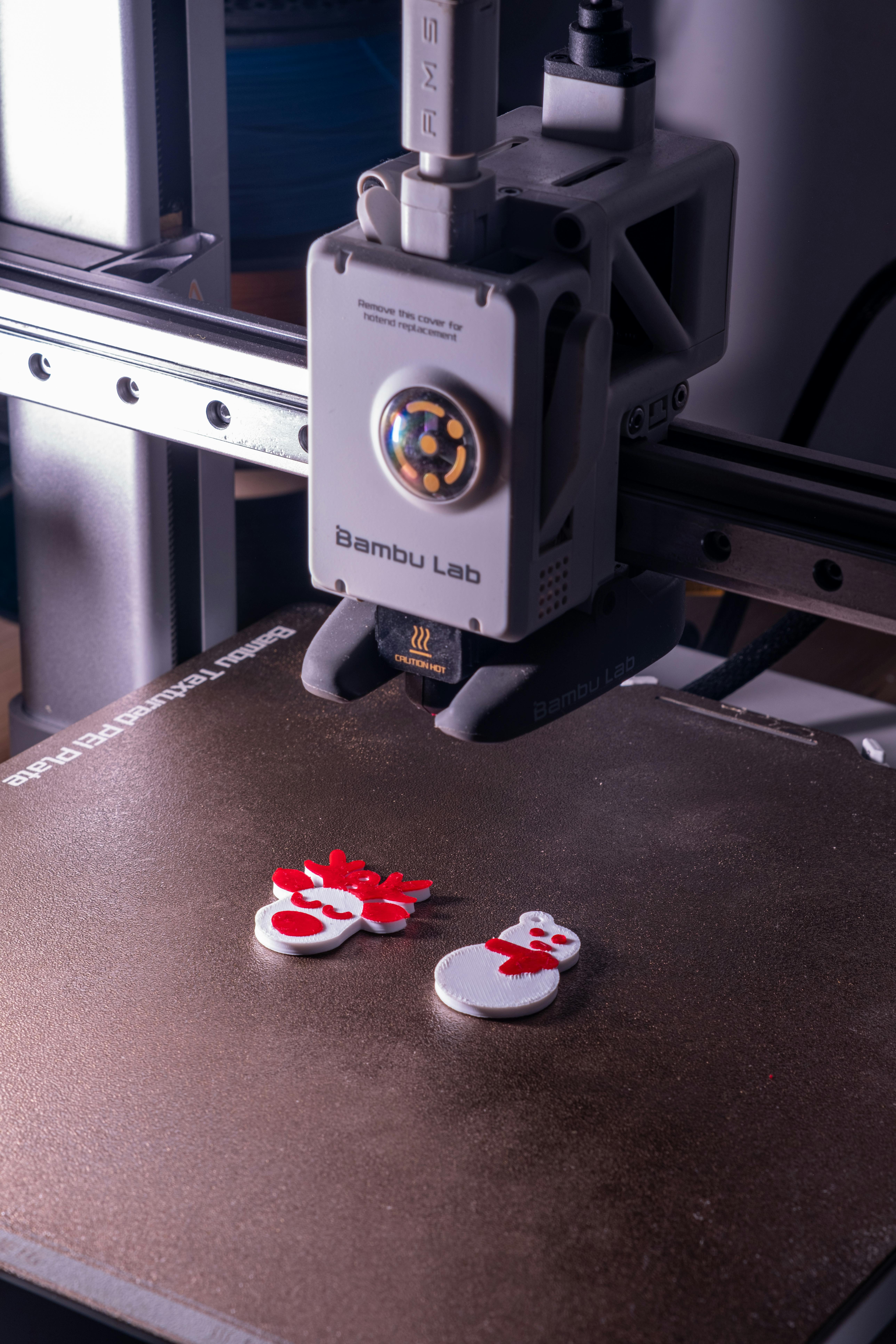 Bambu Lab FDM printer actively building parts on the build plate, illustrating a job in production